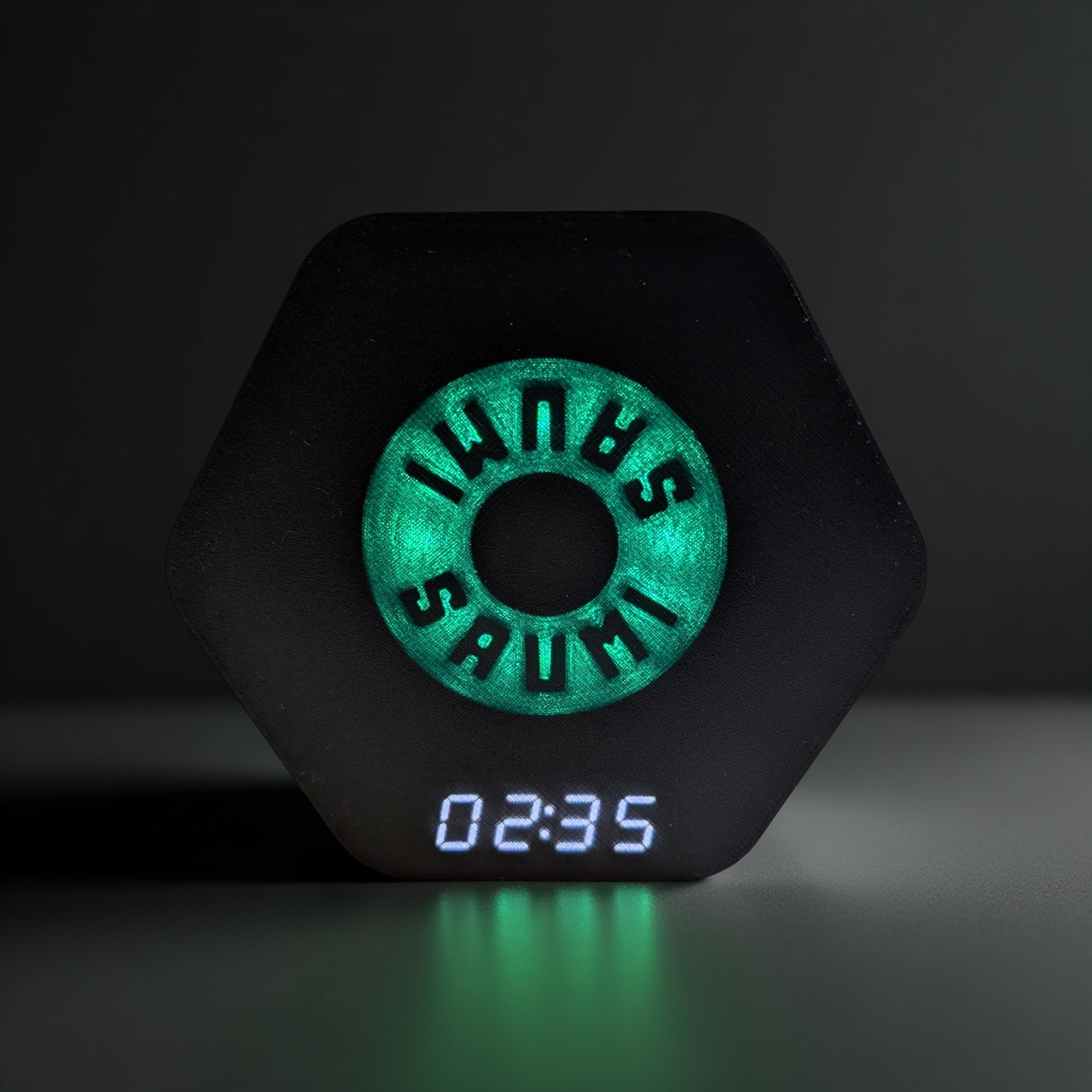 SAUMI the drinking timer in a frontal view. The green LEDs are lighting up and the white display shows 2:35 seconds